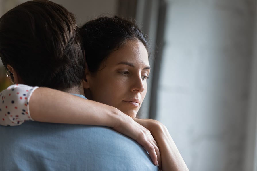 Unhappy young woman hugging husband